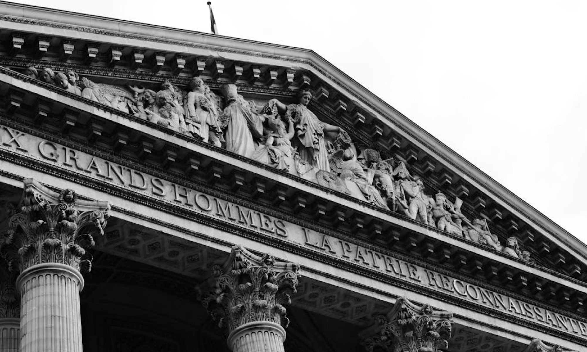 Striking black and white photo of the Pantheon facade in Paris, capturing detailed sculptures and architecture.